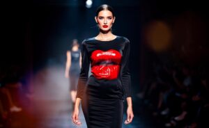 Illustration von einem Model auf dem Laufsteg, das ein schwarzes Kleid trägt, auf dem sich ein täuschend echter, glänzender Lippenstiftabdruck als dreidimensionale Applikation abzeichnet.